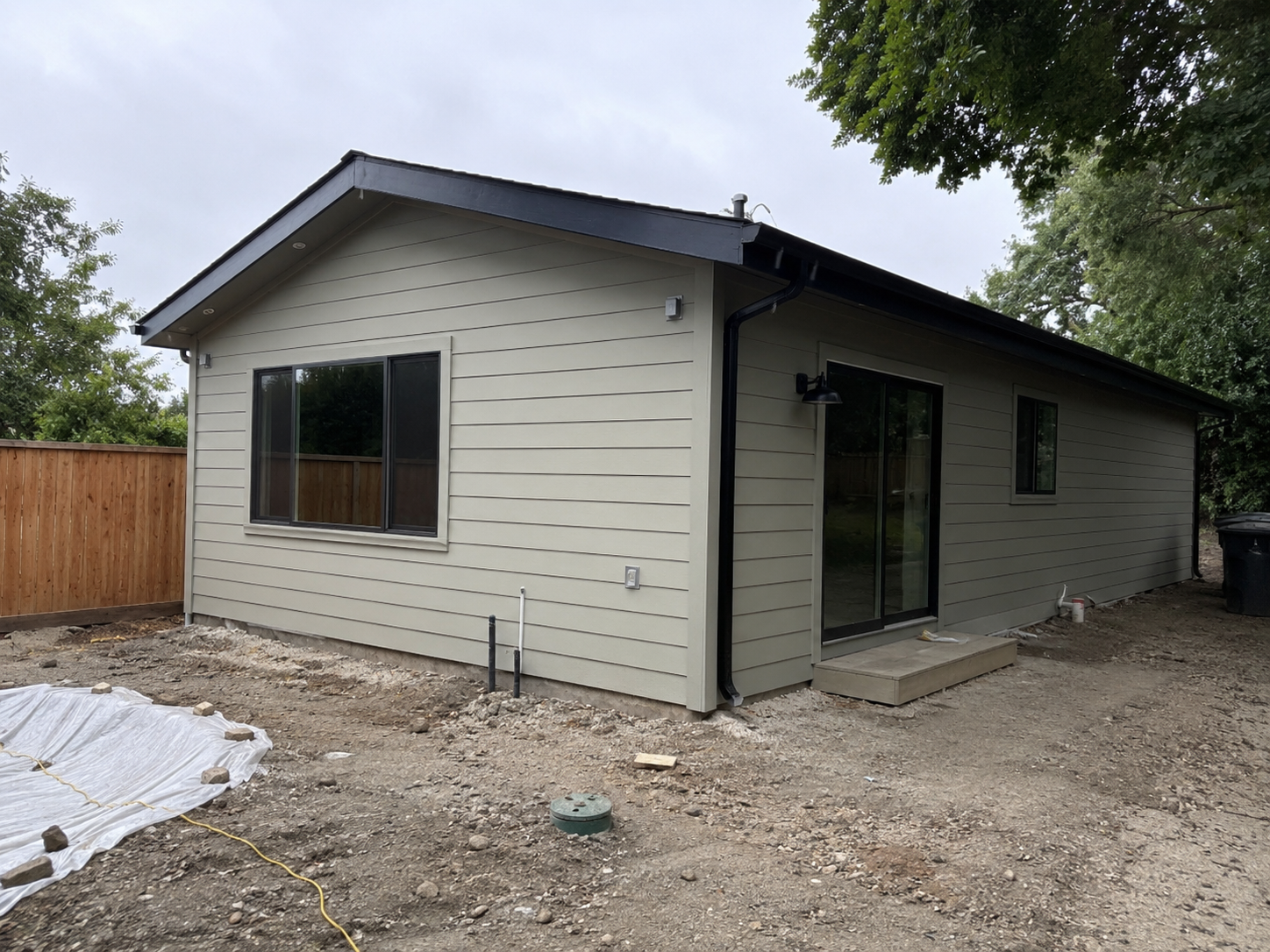 Recently completed Plano backyard ADU with sage Hardie lap siding, dark trim, and sliding glass door
